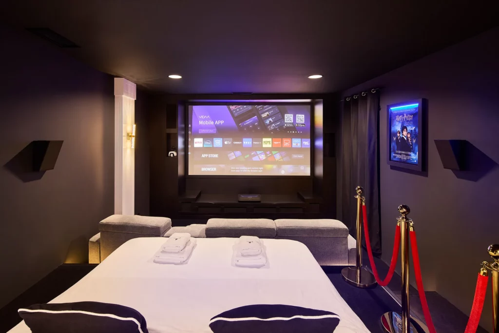 Grand lit double devant écran de cinéma : dormez dans un vrai cinéma privé, love room Niort par Atypique Room.